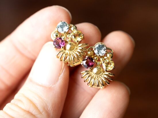 holding gold gemstone earrings