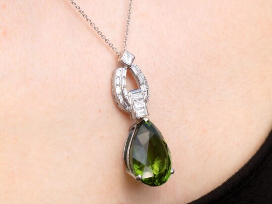 Pear shaped peridot pendant in platinum with diamonds being worn