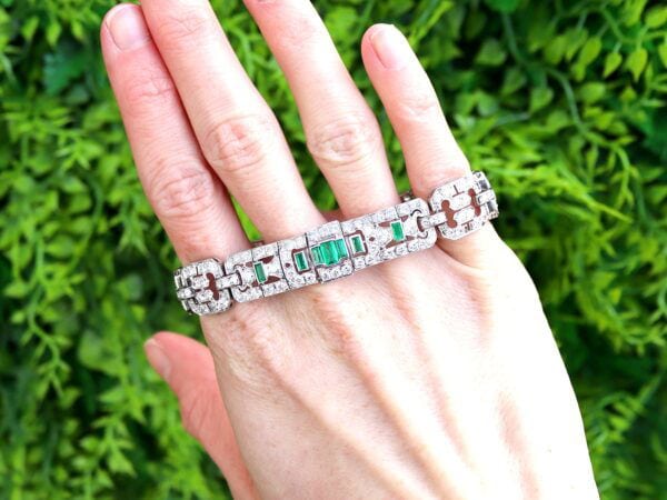 holding a platinum Art Deco emerald and diamond bracelet