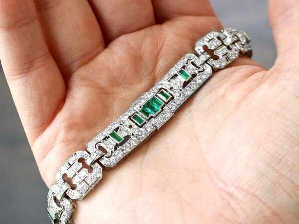holding a 1920s platinum emerald and diamond bracelet