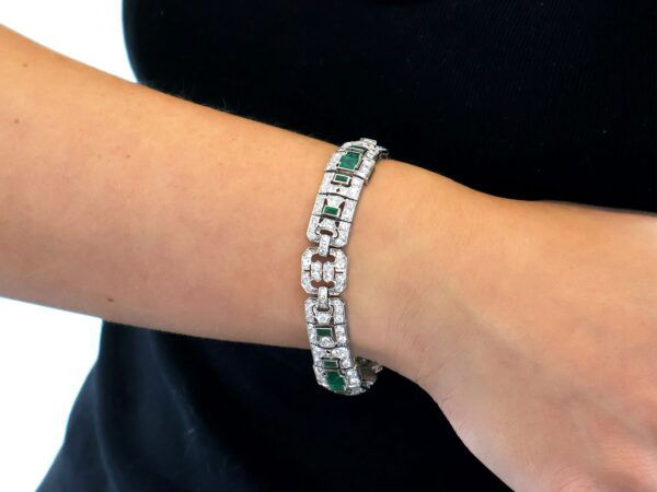 wearing a platinum Art Deco emerald and diamond bracelet