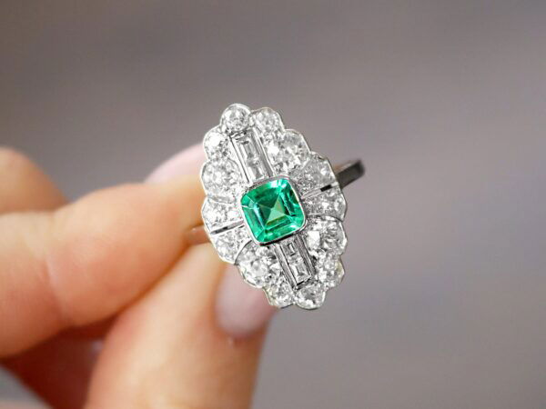 holding art deco emerald and diamond ring