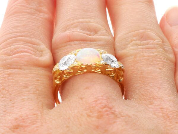 wearing a gold opal and diamond trilogy ring