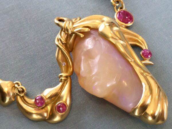 close up gold carved opal and ruby necklace
