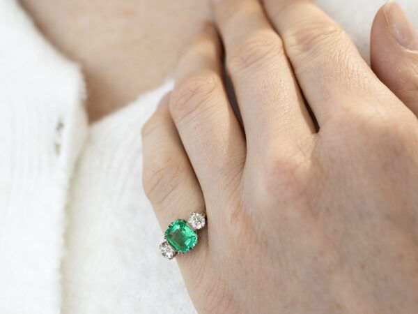 emerald trilogy engagement ring in gold on finger