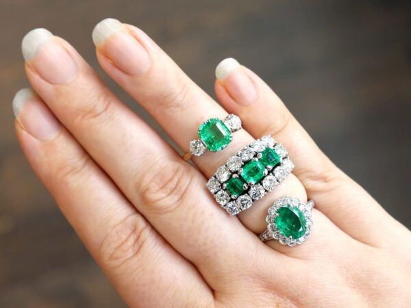 wearing emerald trilogy engagement ring with other emerald rings