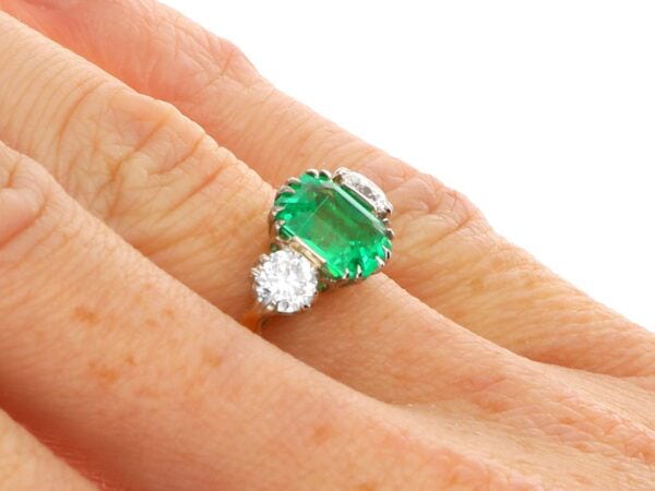 emerald trilogy engagement ring in gold on finger