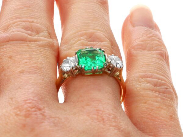 emerald trilogy engagement ring on finger