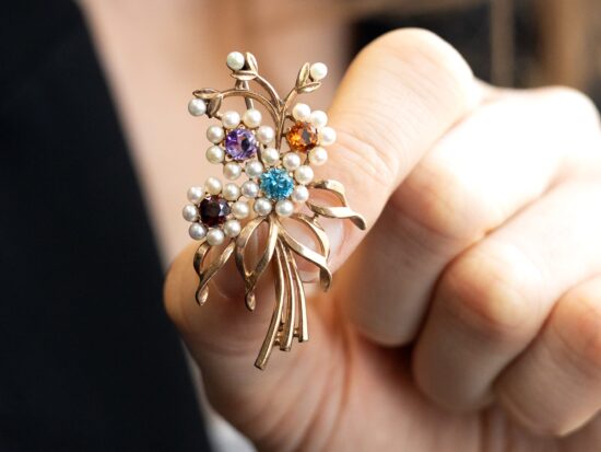holding gold gemstone brooch