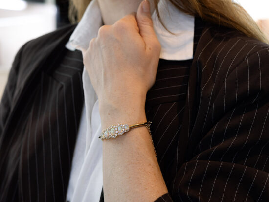 Victorian opal and diamond yellow gold bangle being worn