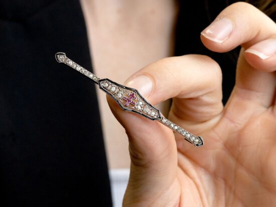 holding an onyx and ruby brooch