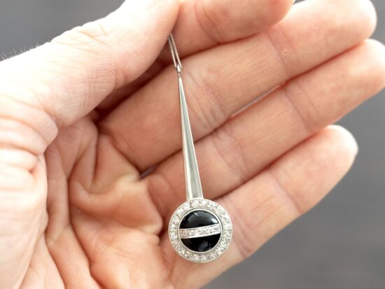 holding an onyx and diamond pendant