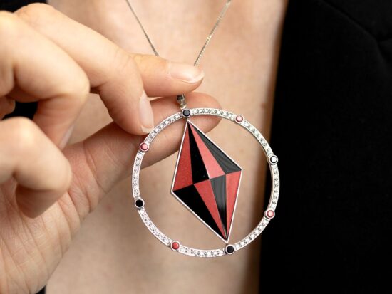 holding a coral and onyx pendant