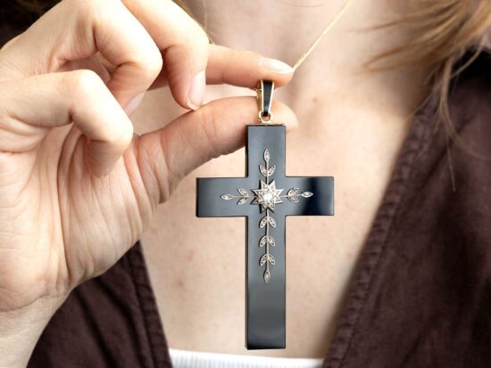 holding an antique onyx cross pendant