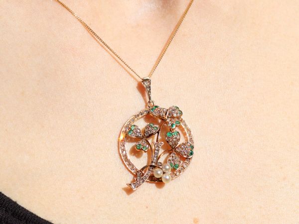 circular gold pendant with pearls and emeralds on the neck