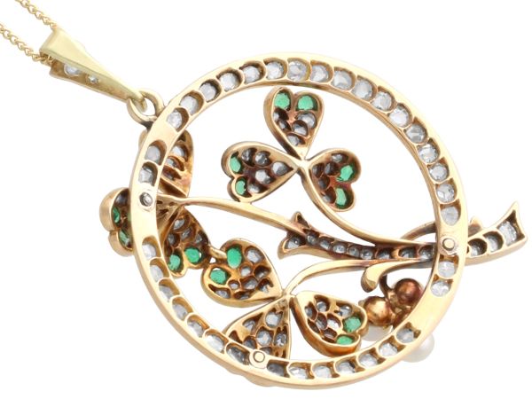 underside of circular gold pendant with pearls and emeralds