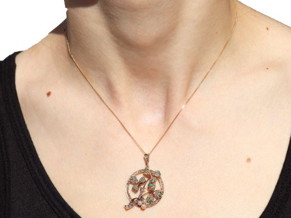 wearing circular gold pendant with pearls and emeralds