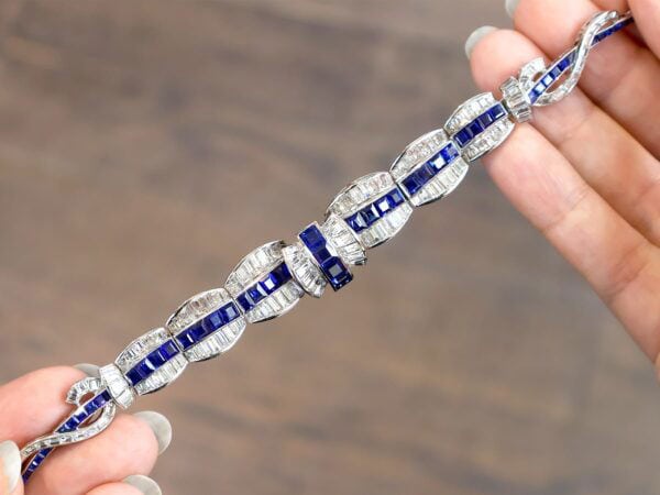 holding an art deco sapphire necklace